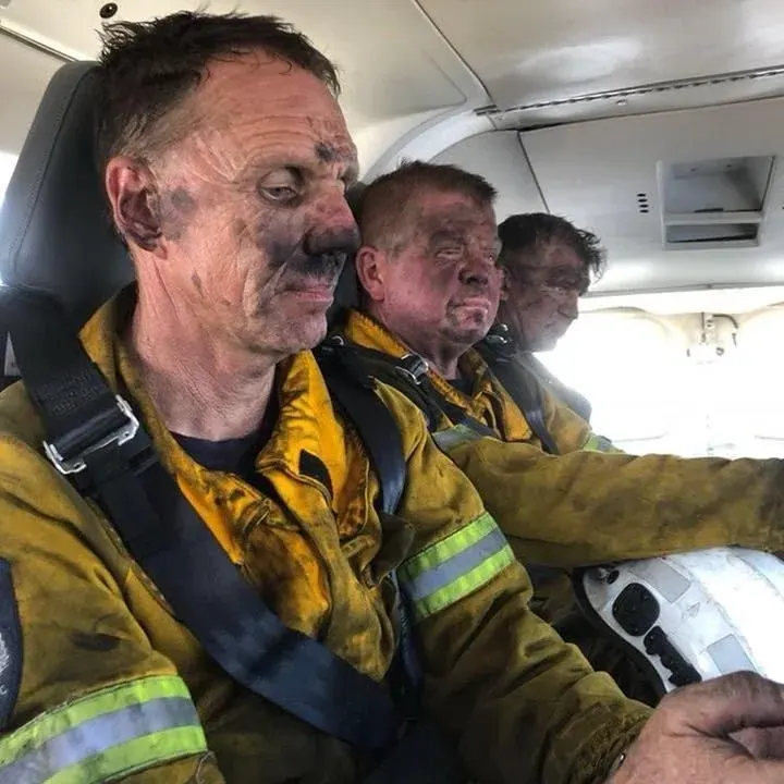 Bomberos con el rostro y el EPP cubiertos de hollín después de una emergencia